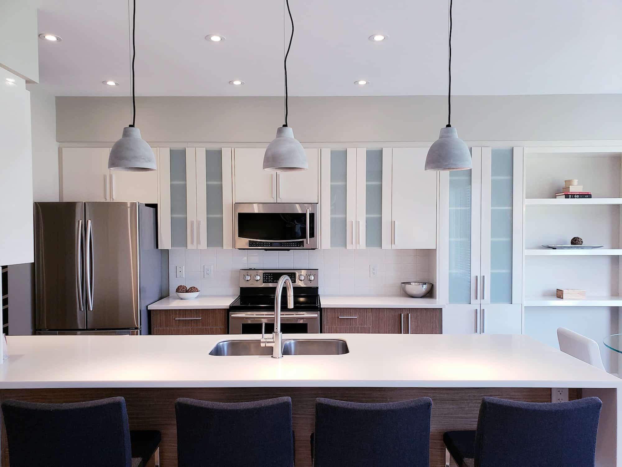 Modern design kitchen cabinets in white and tinted glass, quartz countertop, lights fixtures